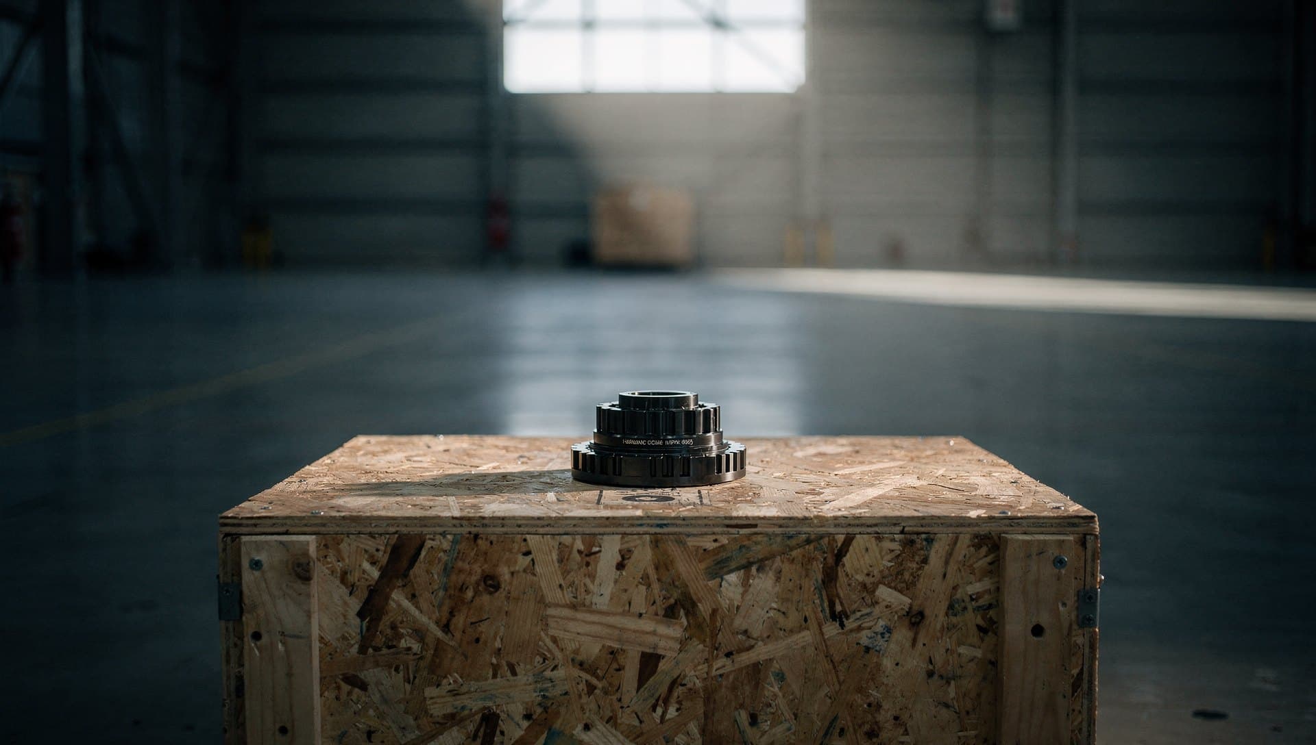 A machined gear resting on a shipping crate in an empty cargo terminal